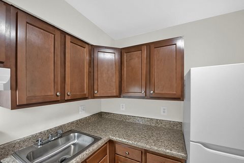 a kitchen with wood cabinets and granite counter tops and a stainless steel sink